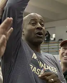 Moncrief raising his hand in the air, surrounded by veterns on a basketball court