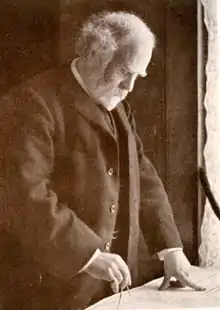 Sir John Murray in his later years, bearded and drawing or measuring with a compass.