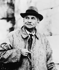 Photograph of a man in late middle age, wearing an anorak and with slightly greying hair, in front of a stone wall.