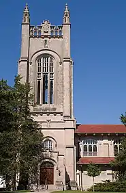 The stone tower of the chapel. There are some decorative elements at the top and the rest of the chapel extends to the right.