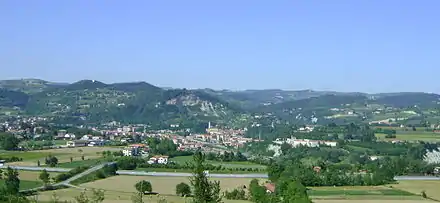 Photo of a town with a river in the foreground and mountains in the background