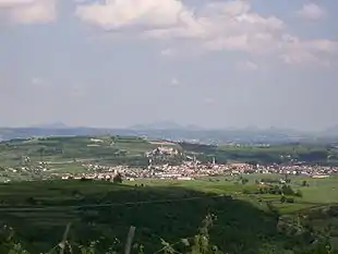 Photo of a town in a valley with a ridge rising behind and mountains in the distance