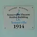 The historical marker sign on the face of the Somerville Theatre Hobbs Building