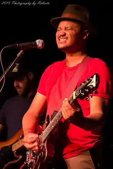 Son Little with his eyes closed and playing a guitar