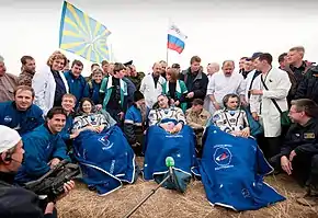 Tracy Caldwell Dyson, Alexander Skvortsov and Mikhail Kornienko sit in chairs outside the Soyuz capsule just minutes after they landed.