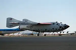 A white rocketship with oddly-shaped wings at rest on a runway. (from Outer space)