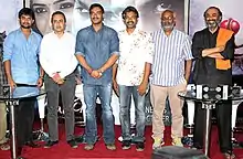 Nani, Sanjeev Lamba, Ajay Devgan, Rajamouli, Keeravani and Suresh Babu stand and look towards the camera.