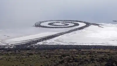 Robert Smithson's monumental graphic art earthwork Spiral Jetty (1970) is located on the Great Salt Lake in Utah. Using black basalt rocks and earth from the site, the artist created an artistic composition in the translucent red water with a graphic design 1,500 feet long and 15 feet wide.