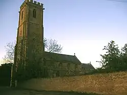 Stone building with square tower, partially obscured by trees