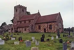 Sandstone church with square tower standing in graveyard.