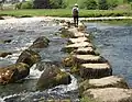 Dales Way walker's view of stepping-stones across Wharfe, toward Linton Church