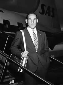 A black and white photograph Stirling Moss smiling at the camera