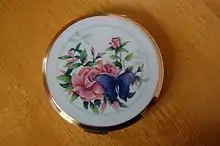 Circular brass container with lid depicting a rose and a butterfly