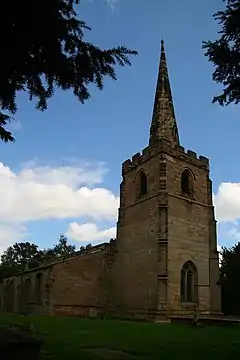 In the foreground is the tower of a stone church with a recessed spire, and the body of the church extends beyond it