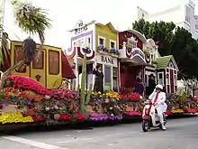 Rose Parade float with white coat volunteer