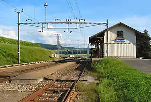 Two-story building with gabled roof next to double-tracked railway line