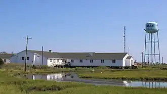 A long white building on stilts surrounded by marsh