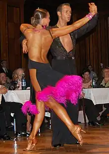 Image 23Latin dancers in their costumes. The woman is wearing backless dress with deep slits on its lower portion, while the man is wearing a shirt with top buttons open. (from Fashion)