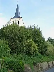 The stone bell tower, of a brilliant white due to a recent restoration, emerges from the wooded hill overlooking a part of the village.