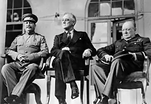 Three men, Stalin, Roosevelt and Churchill, sitting together elbow to elbow