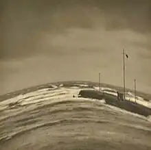 Photograph looking out to the sea, with a breakwater and, above this, a windsock. See also the adjacent text.