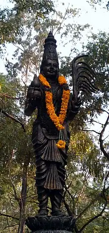 Black outdoor statue with an orange garland