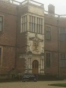 Photograph of entrance porch of Temple Newsam House, Leeds, showing at top the word 'FATHER', below a mullioned window, below a raised portico with coat of arms above a doorway flanked by two Ionic columns on each side.