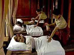 Two masseurs massaging their clients using stretching.