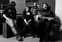 Black-and-white photograph of The Magic Numbers sitting in a recording studio in 2009