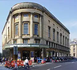 Yellow stone triangular building with four columns above the semicircular entrance.