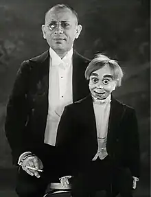 A man holds a ventriloquist dummy