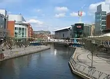 Stretch of canal with large modern buildings and concrete walkways on either side.