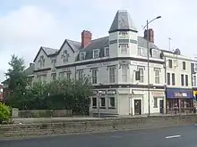 Photograph of a hotel and shops along a road