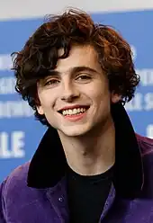 Timothée Chalamet standing in front of a blue background at the 67th Berlin International Film Festival in 2017