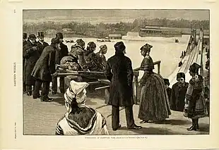 A winter scene.  Men, women, and children are at the top of a hill, boarding toboggans preparing to slide down one of two tracks.  Horses pulling sleds are visible in the distance, along with several buildings.