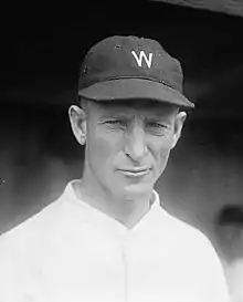 A wearing a white baseball jersey with a dark cap with a white "W" on the center.