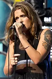 A dark-haired woman performs with a microphone