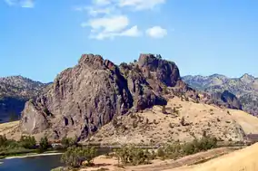 Image of an igneous rock formation with two peaks near a river