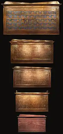 Five box-like structures of diminishing size. The first four are gilded and the smallest one stone.