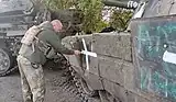 Soldier of the 17th Tank Brigade painting a cross on a captured tank