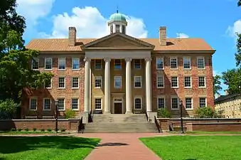 A large building with many windows and four columns on the front.