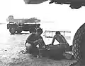 US Navy maintenance crews VB-106 clean engine parts under an airplane wing while raining at Momote Airfiled in March 1944 at  Manus Naval Base