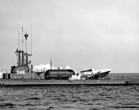 A rocket taking off horizontally from the deck of a surfaced World War II-era submarine