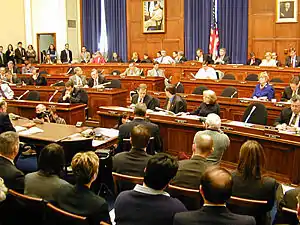 House Financial Services committee members sit in the tiers of raised chairs, while those testifying and audience members sit below.