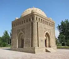 A cuboid building with a dome, in a greenery-enclosed plaza.