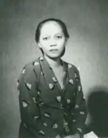 Image of an Asian woman with her hair pulled back wearing a dark dress with light colored geometric designs.