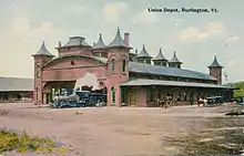 A postcard of a railway station with a large arched trainshed