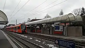 Red train arriving at side platform on double track line