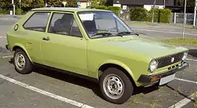  Front-three-quarter view of a small three-door car with steel wheels and no passenger-side door mirror.