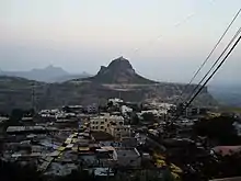 Cluster of homes at the bottom with a hill in background. IMage is taken from another hill.